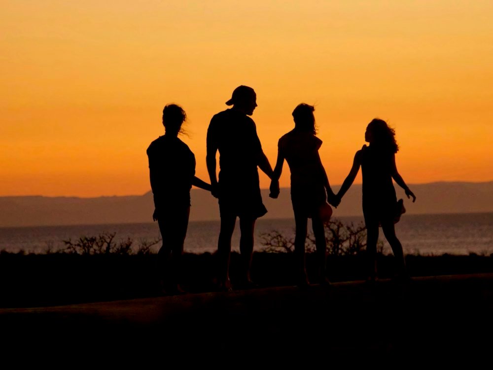 Família de mãos dadas ao pôr do sol